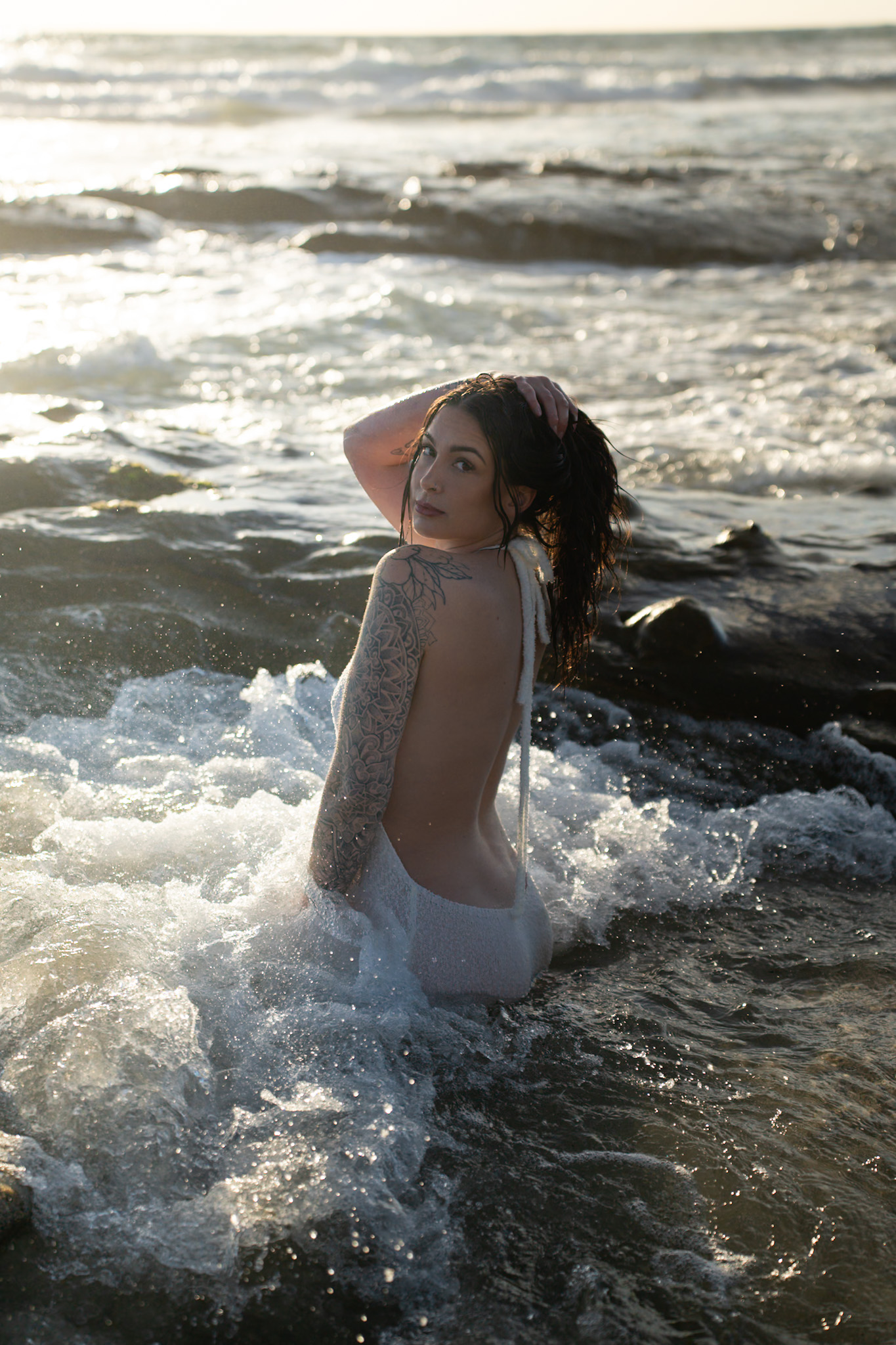 Woman wearing a white dress standing in ocean waves